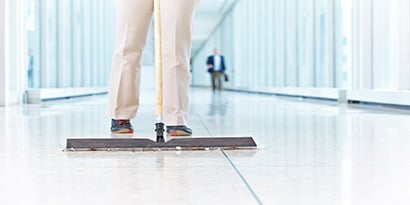 A custodian using 3M East Trap Dust sheet to mop the floor