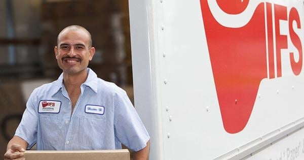 IFS truck driver in front of IFS logoed truck holding a box for delivery