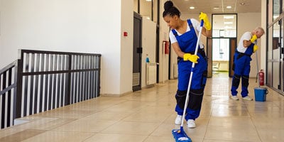 two janitors wiping the floor of commercial building or school hallway