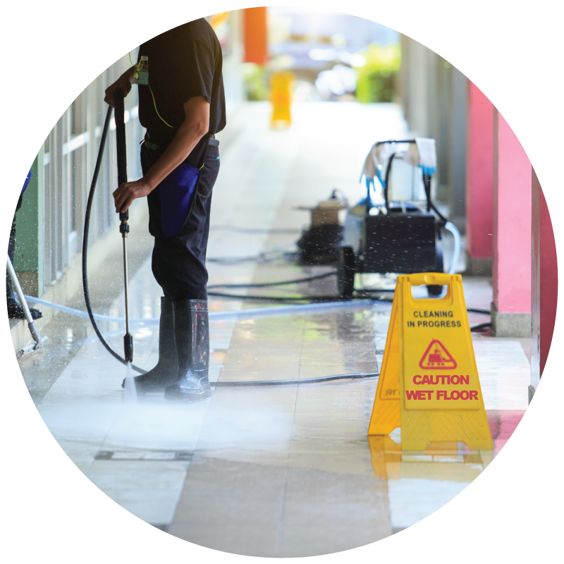 A custodian pressure washing the building floor