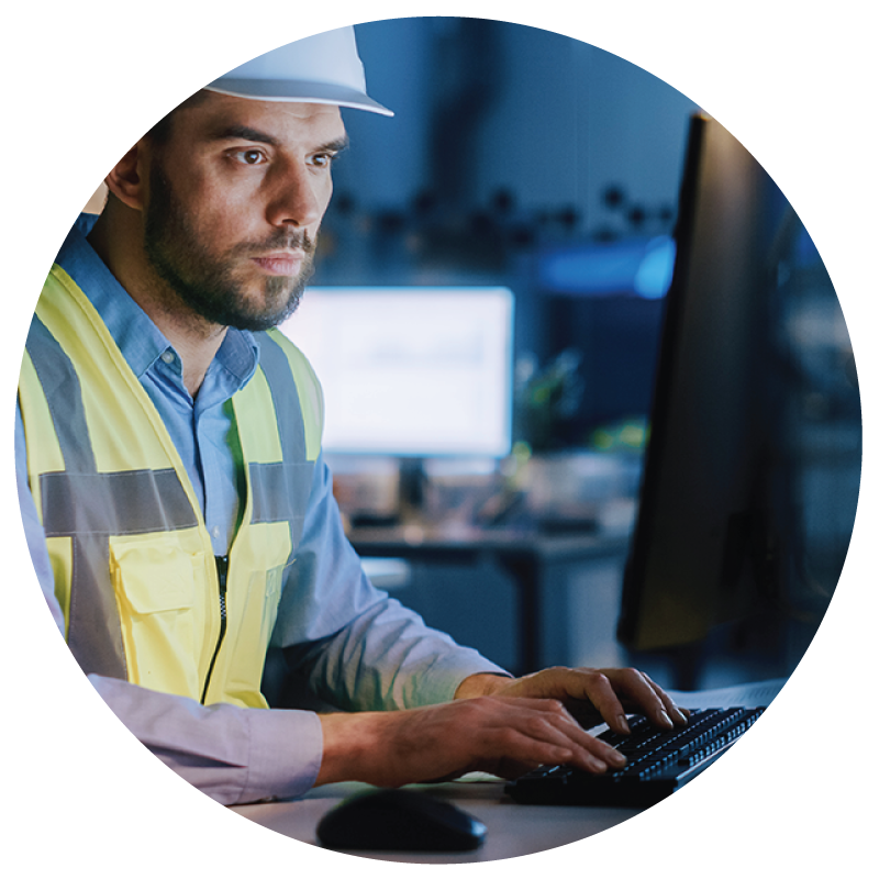 A facility manager with hard hat looking in his computer