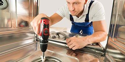 technician fixing dishwasher