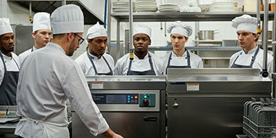 kitchen staff getting trained on commercial kitchen equipment