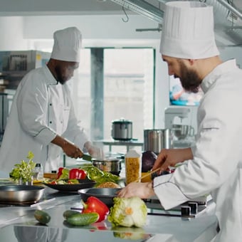 Two chefs making food in a commercial kitchen