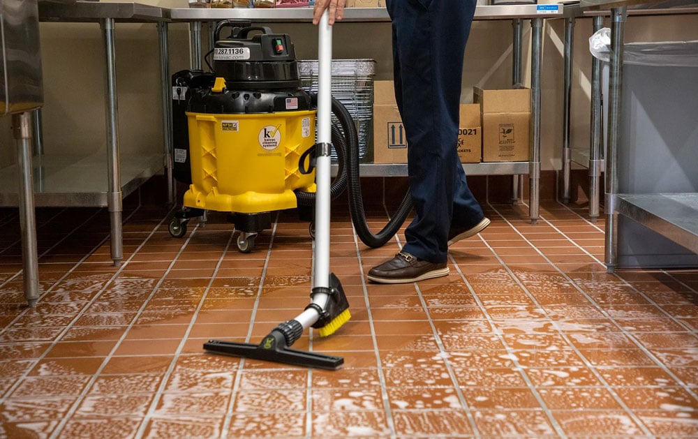 A staff cleaning floor with Kaivac Univac vacuum