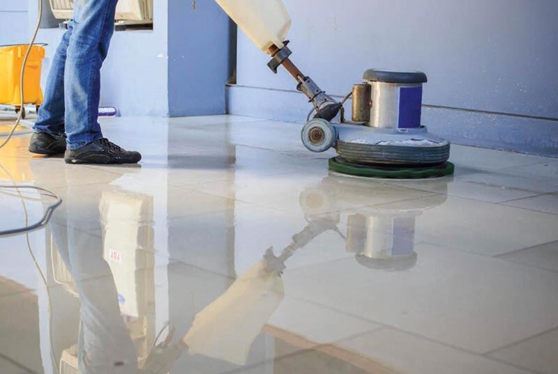 a custodian buffing the floor using a buffing scrubber