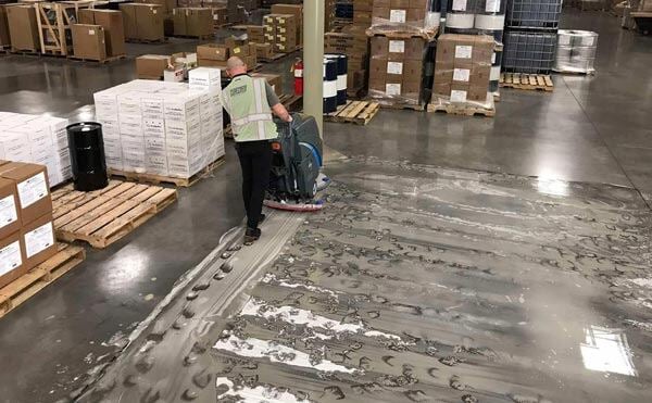 a facility staff restoring warehouse floor using machine